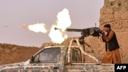 FILE - A member of an anti-Taliban militia fires a machine gun during a fight with Taliban insurgents in Mukhtar, on the outskirts of Lashkar Gah, Afghanistan, March 28, 2021. Government forces battled a Taliban assault on Lashkar Gah on July 31, 2021,