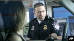 FILE - U.S. Customs and Border Protection officer Kevin Corsaro speaks with a motorist entering the United States, June 6, 2006. The U.S. Customs and Border Protection agency says it has increased its searches of electronics.