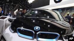 FILE - In this Wednesday, April 17, 2019 file photo, a worker cleans an electric vehicle at the BMW booth during the Auto Shanghai 2019 show in Shanghai. 