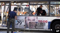 以色列警察11月21日在特拉维夫一个爆炸的地点检查受到损坏的巴士