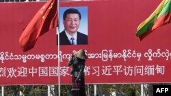 ស្ត្រី​ម្នាក់​កំពុង​ស្រោច​ទឹក​នៅ​មុខ​ប៉ាណូ​ដែល​ស្វាគមន៍​លោក​ប្រធានាធិបតី​ចិន Xi Jinping នៅ​រដ្ឋធានី​​ណៃពិដោរ កាល​ពី​ថ្ងៃ​ទី​១៧ ខែ​មករា ឆ្នាំ​២០២០។ 