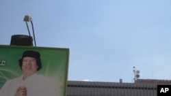 In this photo taken on a government-organized tour, a billboard depicting Libyan leader Moammar Gadhafi stands at the entrance to the international airport in Tripoli, Libya, Saturday, Aug. 20, 2011.