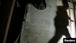 A shadow of a migrant enforcement officer is cast on a makeshift shelter, built by suspected illegal migrant workers, as he tries to break a locked door during a crackdown on illegal migrant workers in Nilai, outside Kuala Lumpur September 1, 2013. 