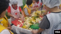 27일 중복을 맞아 하나원 교육생들과 적십자사 회원들이 쪽방촌 주민들에게 삼계탕을 나눠주는 봉사활동을 했다. 참가자들이 삼계탕과 함께 먹을 김치를 만들고 있다.