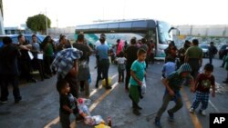 Sejumlah migran tampak menunggu di luar pusat penampungan migran di Jembatan Internasional 1, sebelum menaiki bus dari Nuevo Laredo menuju Monterrey, Meksiko, pada 16 Juli 2019. (Foto: AP/Marco Ugarte)