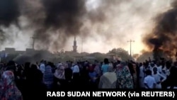 Orang-orang berkumpul di jalan saat asap mengepul di Khartoum, Sudan, di tengah laporan adanya kudeta di negara itu, 25 Oktober 2021. (Foto: RASD SUDAN NETWORK via REUTERS)