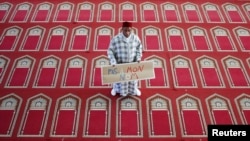 FILE - Muslim Khaloar Abdarahim holds a placard which reads "Not in my name" as he poses inside the Arrahma Mosque after Friday prayers in Nantes, western France, Sept. 26, 2014 after a gathering to pay tribute to French mountain guide Herve Gourdel who was beheaded by an Algerian Islamist group.