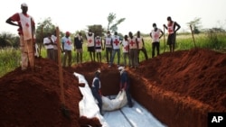 Workers from the Central African Red Cross bury 13 victims of sectarian violence in a mass grave, in Bangui, Central African Republic, Jan. 5, 2014. 