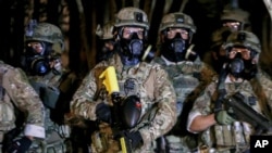 Police stand as protesters gather during a demonstration, July 16, 2020 in Portland, Ore. Federal officers deployed tear gas and fired less-lethal rounds into a crowd of protesters late Thursday. 