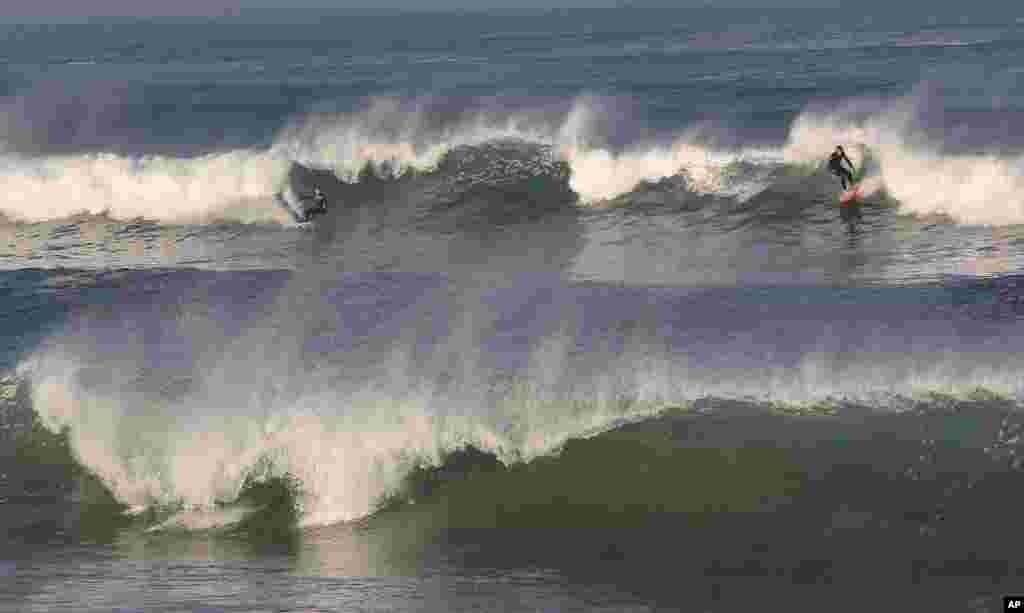 Para peselancar berselancar di antara ombak Samudra Atlantik di tengah cuaca yang tidak biasanya hangat di Anglet, baratdaya Prancis.