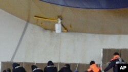 Italian Coast Guard scuba divers carry away the recovered bodies of two victims of the grounded cruise ship Costa Concordia off the Tuscan island of Giglio, Italy, Jan. 23, 2012.