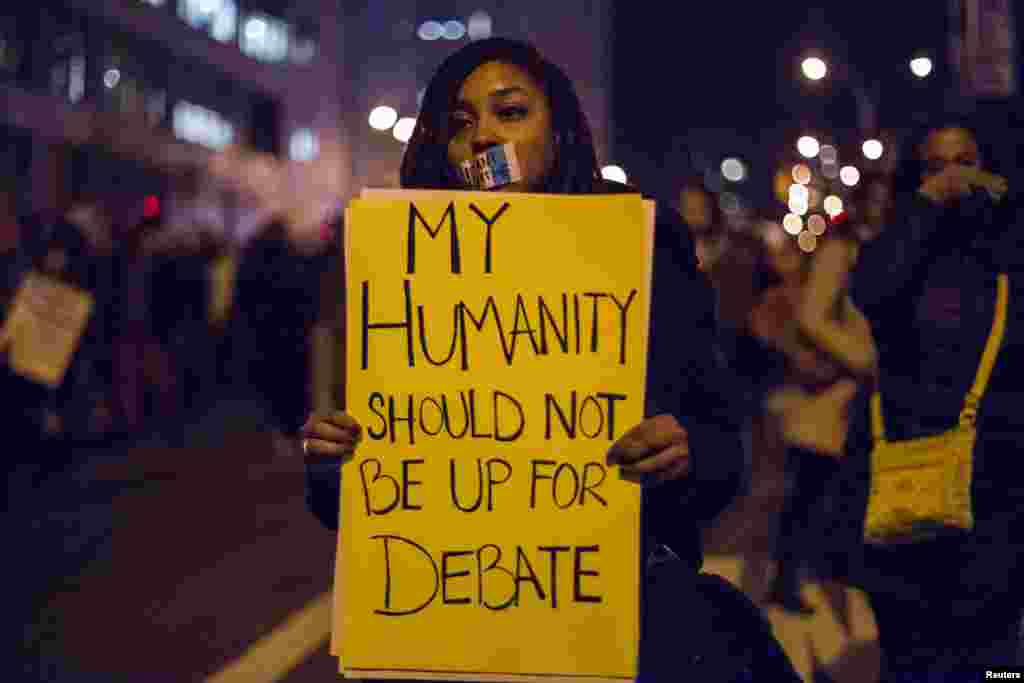 A female protester, demanding justice for Eric Garner, holds a placard in Brooklyn in New York, Dec. 4, 2014.