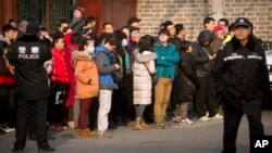 FILE - Chinese policemen watch as depositors from Ezubao gather outside the State Bureau for Letters and Calls Reception Division office in Beijing, Jan. 1, 2016. China's policy ministry says it investigated 380 online lenders following an avalanche of scandals.
