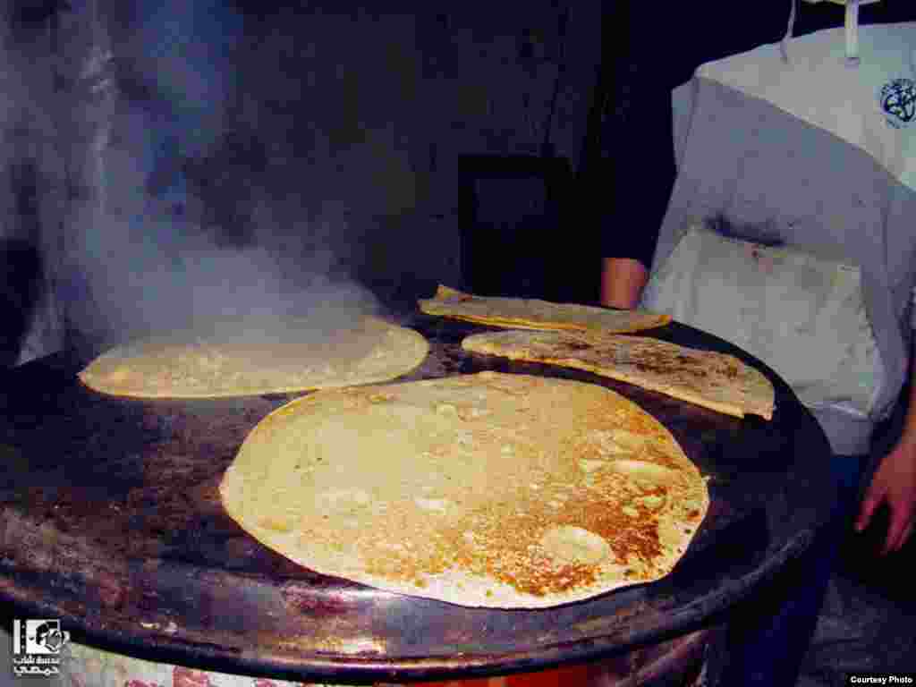 Pembuatan roti di atas batu panas di sebuah rumah di kota Homs (4/1). (Lens Young Homsi)