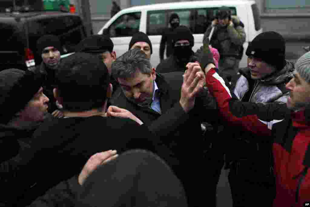 A suspected supporter of Ukraine&#39;s embattled President Viktor Yanukovych, center, is assaulted by anti-government protesters in Kyiv.