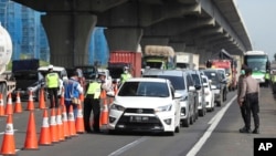 Para petugas kepolisian mengecek mobil-mobil di jalan tol Cikarang, Jawa Barat, untuk mencegah warga agar tidak mudik lebaran di tengah pandemi virus corona, 24 April 2020.