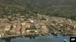 In this Jan. 21, 2020, photo provided by the Philippines Office of Civil Defense, volcanic ash covers roofs of houses near Taal volcano in Batangas province, southern Philippines. 