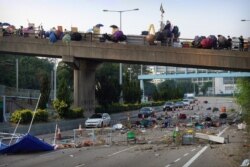 Protesters stand on a barricaded bridge as traffic makes its way underneath near the Chinese University of Hong Kong, in Hong Kong, Nov. 15, 2019.