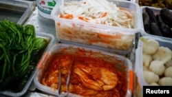 FILE - Korean style pickled cabbage, or Kimchi, and Chinese style pickled vegetables, or Pao Cai, are seen at a supermarket, in Beijing, China December 1, 2020. (REUTERS/Thomas Peter)