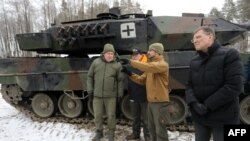 Lithuanian Minister of National Defense Arvydas Anusauskas, left, attends the testing of a Leopard 2 tank at a military training area in Rukla, Lithuania, on Dec. 15, 2023.