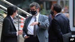 Juan Felipe Amaya, from left, Jaime Granados and Victor Mosquera, lawyers representing senator and former President Alvaro Uribe, talk outside the Supreme Court in Bogota, Colombia, Aug. 4, 2020. 