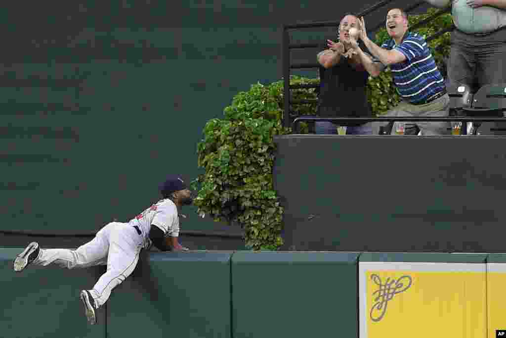 Boston Red Sox center fielder Jackie Bradley Jr., left, watches fans go for a ball hit by Baltimore Orioles&#39; Jonathan Villar for a grand slam during the second inning of a baseball game, May 6, 2019, in Baltimore, Maryland.