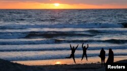 Teenagers pose while having their pictures taken with a phone as the sun sets in Encinitas, California March 31, 2014. 