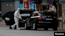 Petugas forensik memeriksa mobil mantan PM Yunani Lucas Papademos setelah bom meledak di dalam mobilnya hari Kamis (25/5).