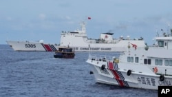 Sebuah kapal Filipina, di tengah, bermanuver di sekitar kapal penjaga pantai China ketika mereka mencoba memblokir jalan di dekat Second Thomas Shoal, di Laut Cina Selatan, 22 Agustus 2023. (Foto: AP)