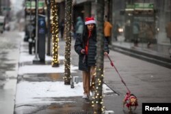 ຜູ້ຍິງຄົນນຶ່ງຍ່າງກັບໝາ ໃນເຂດແມນແຮັດຕັນ ໃນນະຄອນນິວຢອກ, ສະຫະລັດ, ວັນທີ 24 ທັນວາ, 2024. REUTERS/Marko Djurica