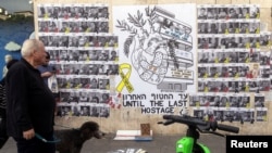 คนเดินผ่านป้ายสนับสนุนการปล่อยตัวประกันในกาซ่า ที่เทลอาวีฟ อิสราเอล 18 ก.พ. 2025 (REUTERS/Nir Elias)