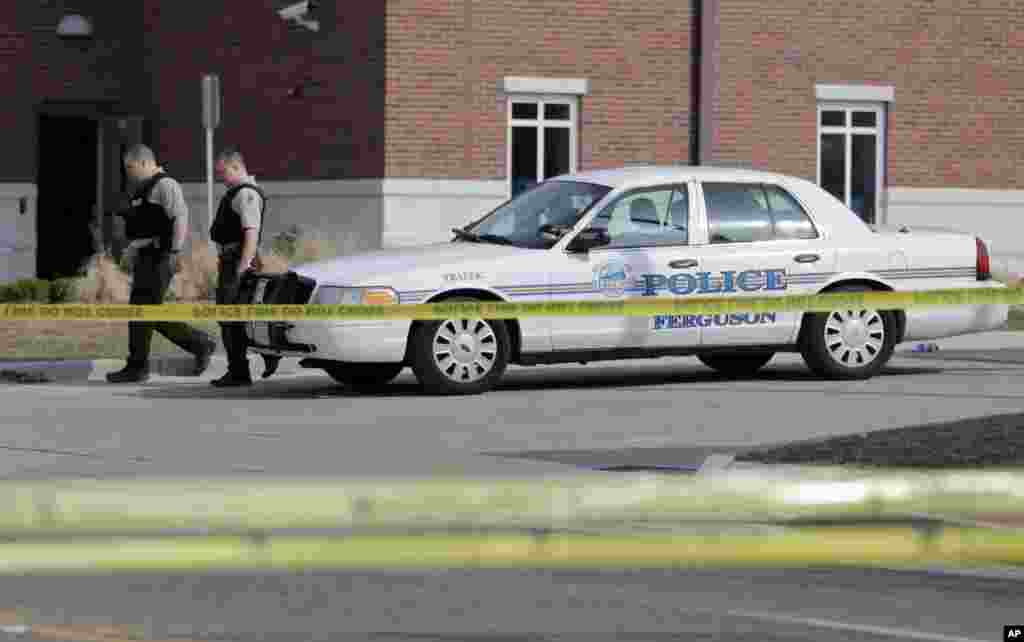 Police officers walk outside the Ferguson Police Department in Ferguson, Mo.