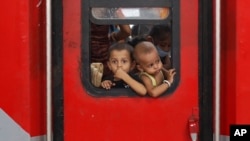 FILE - In this May 30, 2020 photo, Indian migrant worker's children peer out from the window of their train in Prayagraj, India, as they return to villages.