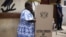 FILE - A woman fills in her ballots in presidential and parliamentary elections at a polling station in Accra, Ghana, Dec. 7, 2012. 
