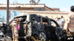 Pasukan keamanan Yaman dan tim penyelamat berkumpul di sekitar bangkai mobil yang terbakar menyusul ledakan yang melanda kota pelabuhan Aden di selatan Yaman, pada 10 Oktober 2021. (Foto: AFP)