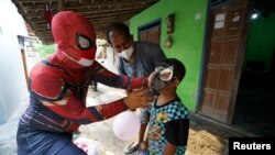 Agus Widanarko, 40, mengenakan kostum superhero saat menghibur anak laki-laki yang ibunya meninggal karena COVID-19, di Sukoharjo, Jawa Tengah, 10 September 2021. (Foto: Reuters)