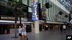 People in masks walk by Binion's casino Monday, June 15, 2020, in Las Vegas.