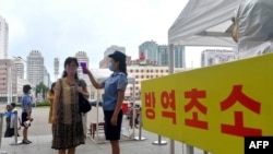 지난 2020년 9월 북한 평양역 입구에서 역무원이 신종 코로나바이러스 방역을 위해 승객들의 체온을 재고 있다. (자료사진)