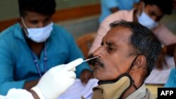 បុគ្គលិកសុខាភិបាលឥណ្ឌាម្នាក់កំពុងយកសំណាកពីមន្ត្រីប៉ូលិសម្នាក់ ដើម្បីធ្វើតេស្តរកជំងឺកូវីដ១៩ នៅខេត្ត Chennai ប្រទេសឥណ្ឌា កាលពីថ្ងៃទី ២ ខែមេសា ឆ្នាំ ២០២១។