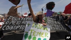 A demonstrator carries a poster written in Portuguese "More Motherland, Less Temer," during a protest after an Independence Day military parade, in Brasilia, Brazil, Sept. 7, 2017. Michel Temer, the president of Brazil, is under investigation for possible obstruction of justice.