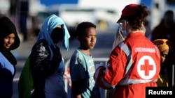 Migrants stand in a line in front of Red Cross member after disembarking from the Italian navy ship Borsini in the Sicilian harbor of Palermo, southern Italy, July 20, 2016.
