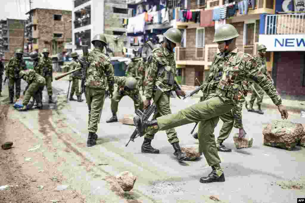 Kenyan police officers clear debris and stones from a barricaded road after a protest by supporters of the National Super Alliance (NASA) opposition coalition presidential candidate at Mathare slum in Nairobi.