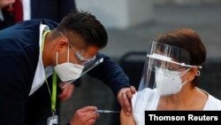 Maria Irene Ramirez receives the first injection with a dose of the PfizerBioNTech COVID-19 vaccine at Ruben Lenero hospital in Mexico City, Dec. 24, 2020.