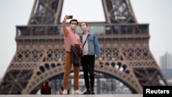 People take a selfie in front of the Eiffel Tower in 2020. A new French dictionary came out, supporting the way the language is spoken outside of France for the first time. (REUTERS/Gonzalo Fuentes)