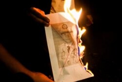 People burn a portrait of Myanmar's army chief, Min Aung Hlaing, as they protest against the military coup in Yangon, Myanmar, Feb. 5, 2021.