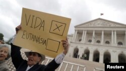 Seorang demonstran mengacungkan poster dalam protes menentang eutanasia di depan parlemen Portugal, di Lisbon, Portugal, 29 Mei 2018. (Foto: Reuters)