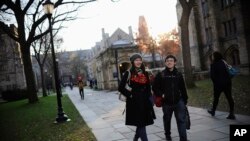 FILE - Yale University sophomore Yupei Guo, left, walks with friend Joseph Lachman on the school's campus in New Haven, Conn., In Nov. 20, 2014. With more undergraduates coming from overseas than ever, some Ivy League universities are reaching out in new 