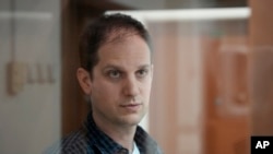 FILE - Reporter Wall Street Journal Evan Gershkovich berdiri di dalam sangkar kaca di ruang sidang Pengadilan Kota Moskow di Moskow, Rusia, 10 Oktober 2023. Pengadilan memutuskan untuk memperpanjang penahanan Gershkovich hingga 30 Januari.(AP Photo/Alexander Zemlianichenko, File)