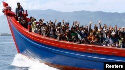 Ethnic Rohingya refugees from Burma wave as they are transported by a wooden boat to a temporary shelter in Krueng Raya in Aceh Besar. (File photo)