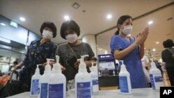 Women wearing face masks to help protect against the coronavirus use hand sanitizer before attending a service at the Yoido Full Gospel Church in Seoul, South Korea, July 5, 2020. 